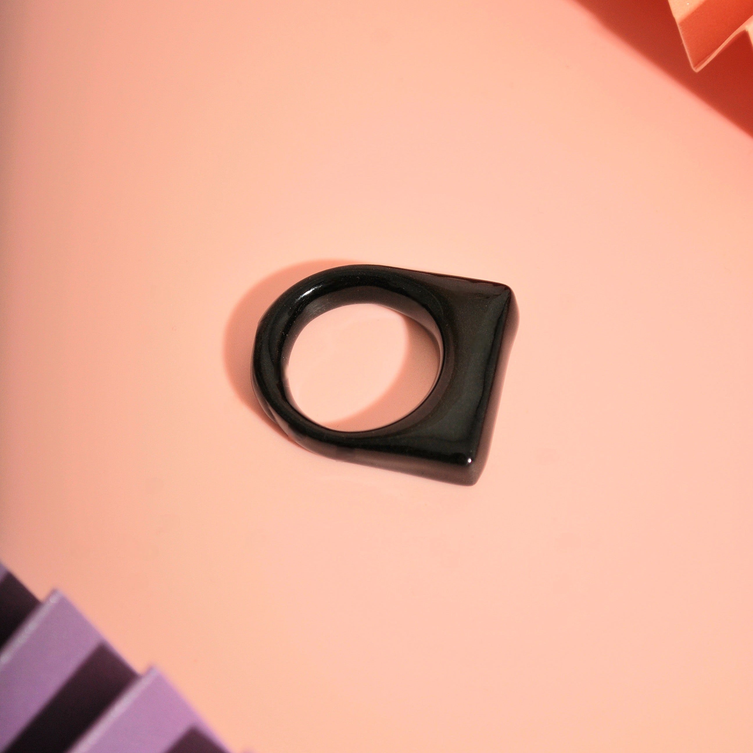 Statement-Ring aus schwarzem Polymer Clay auf rosa Hintergrund