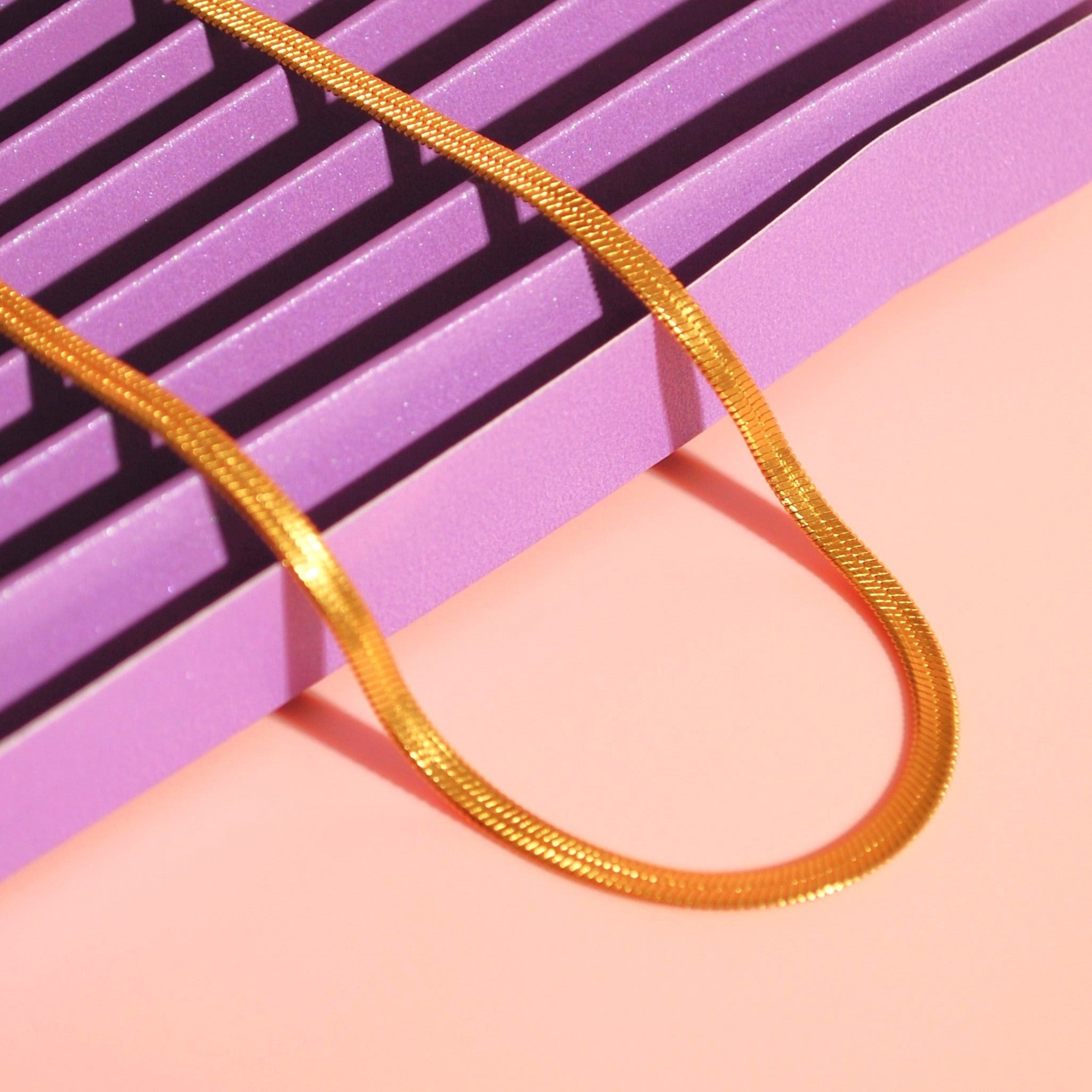 Goldene Layering-Kette auf rosa Hintergrund