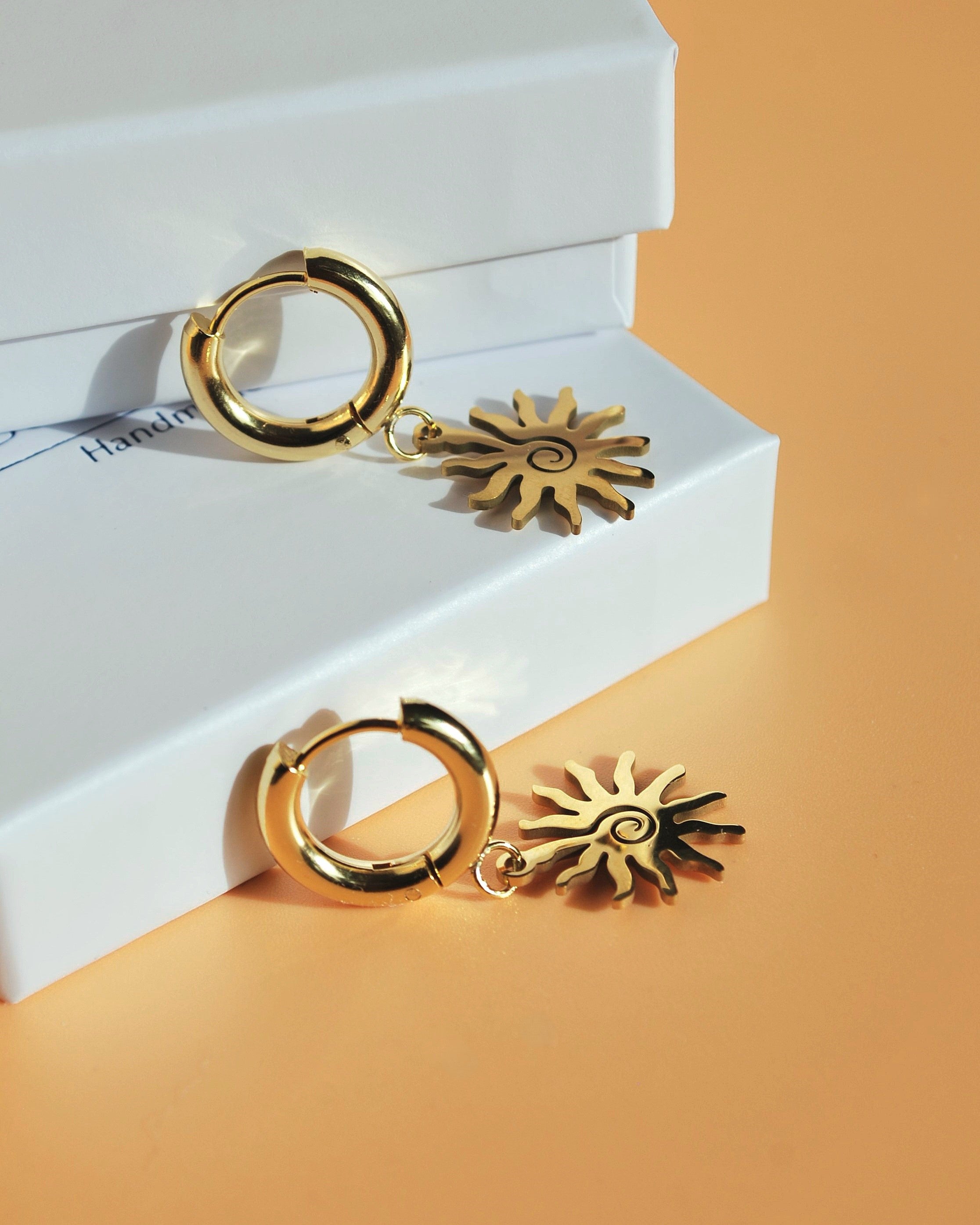 Nahaufnahme der filigranen Creolen mit goldenem Sonnenanhänger – perfekter Sommerschmuck