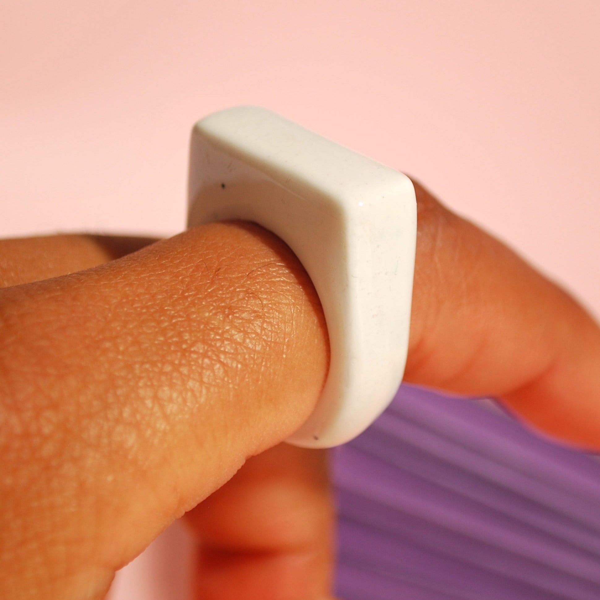 Handgemachter Ring in Weiß auf pastellfarbenem Hintergrund