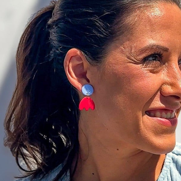 Frau mit dunklen Haaren trägt farbenfrohe Statement-Ohrringe von Santoclay in Lavendel und Rot aus handgefertigtem Polymer Clay mit 24K vergoldetem Edelstahl – fotografiert im Sonnenlicht.