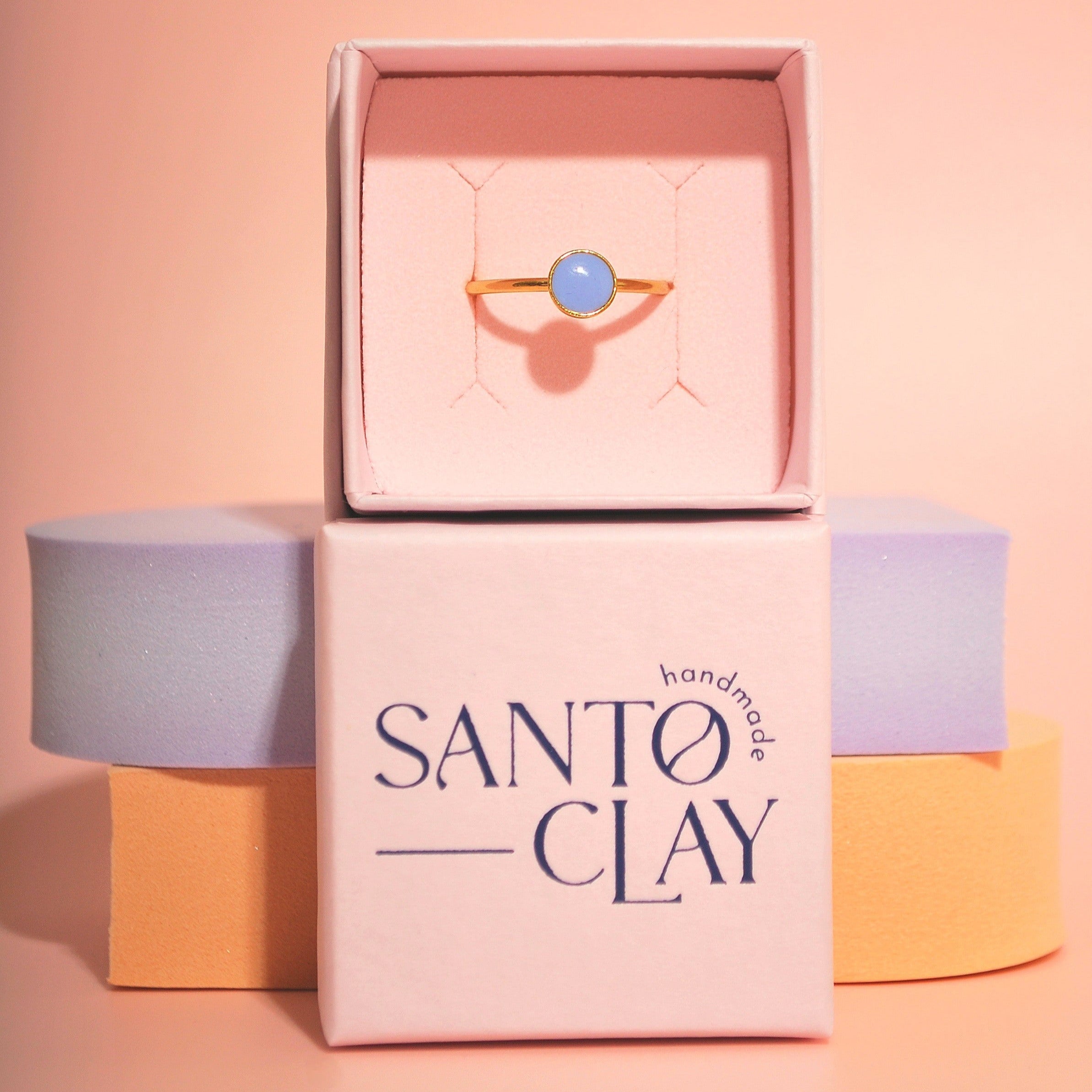 Handgemachter Ring mit lavendelfarbenem Detail aus Polymerton auf Santoclay-Schachtel mit pastellfarbener Dekoration
