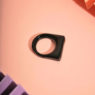 Statement-Ring aus schwarzem Polymer Clay auf rosa Hintergrund