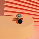 Statement Ring in Schwarz und Marmoroptik auf peachfarbenem Hintergrund