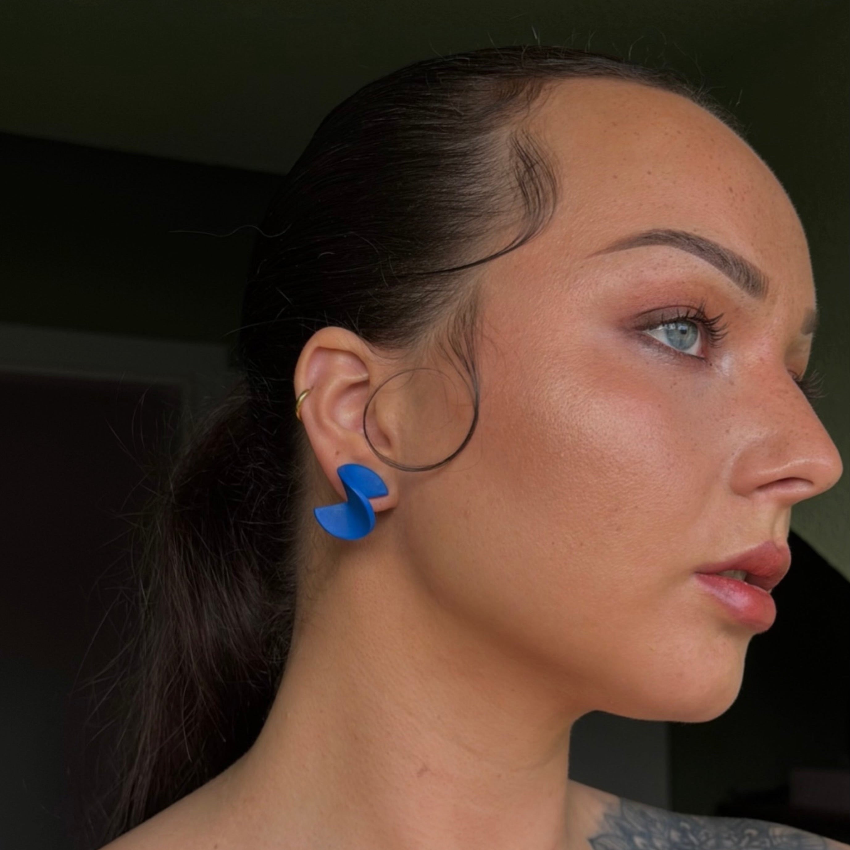 Handgemachter Statement-Ohrstecker in gedrehter Halbkreisform in Blau von Santoclay Handmade, modern am Ohr getragen