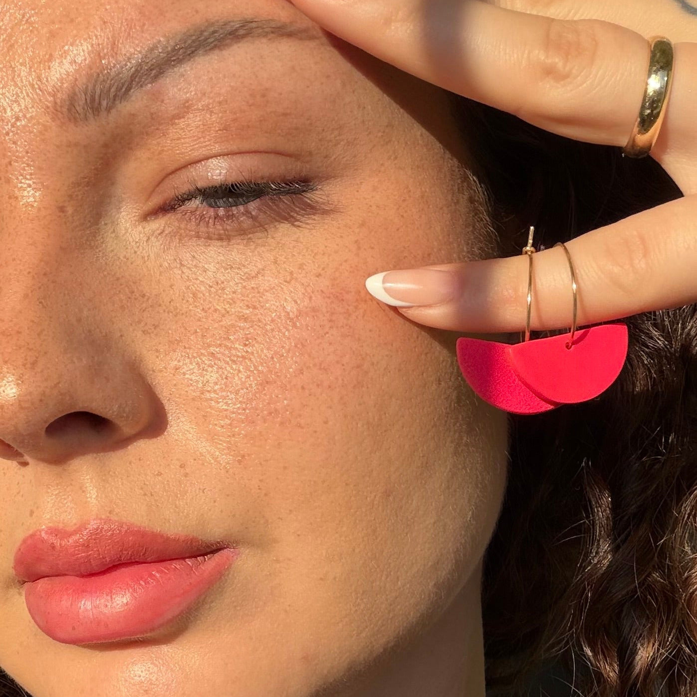 Handgemachter roter Statement-Ohrring in Halbkreisform von Santoclay Handmade, getragen am Ohr, modernes minimalistisches Design