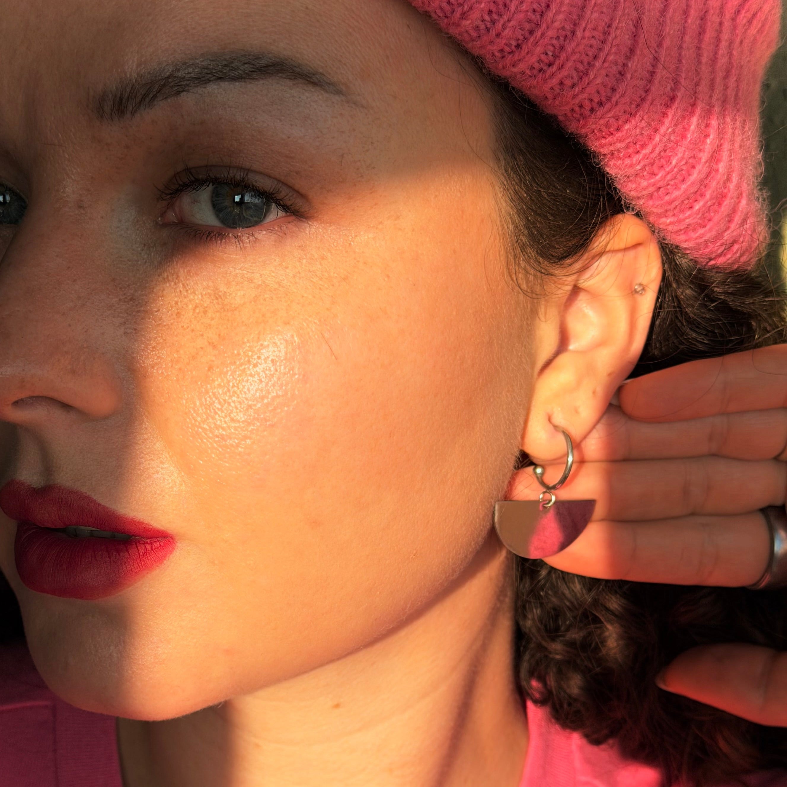 Handgemachte Statement-Ohrringe in Halbkreisform aus silberfarbenem Edelstahl von Santoclay Handmade, am Ohr getragen im Tageslicht