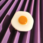 Santoclay Handmade Eggstasy Ring auf violettem Hintergrund