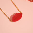 Handgefertigter Schmuck Red Kiss auf rosafarbenem Hintergrund